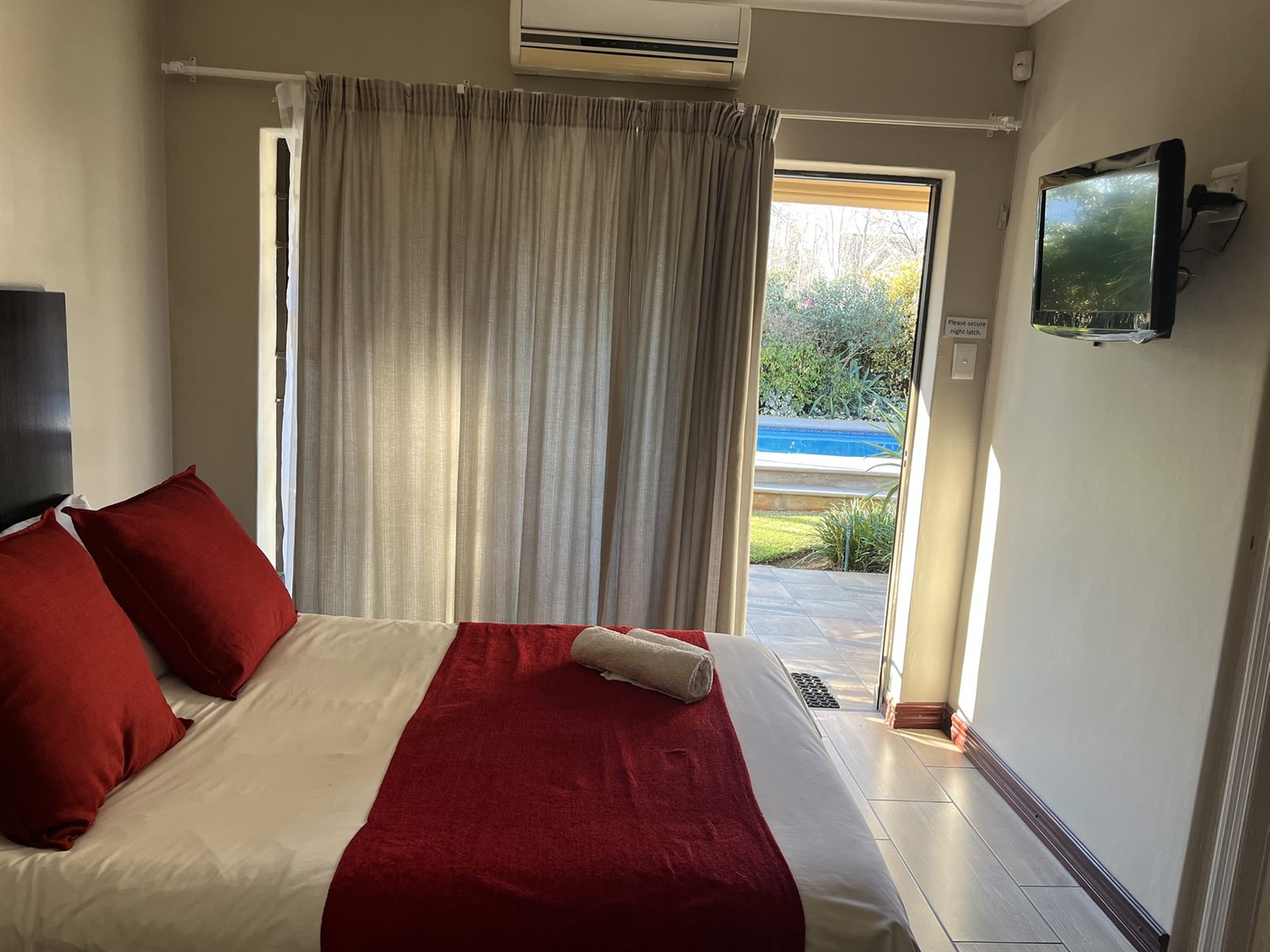 Standard Double Room with Smart TV and patio doors onto the pool garden at Cozy Corner Brandwag