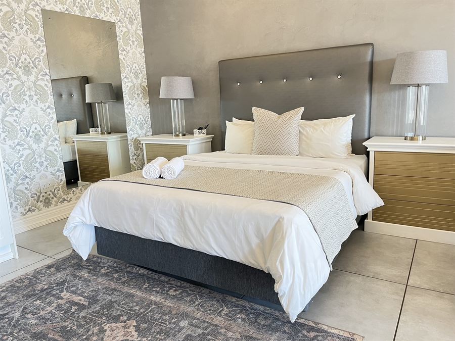 Queen bed against a damask feature wall in the Executive Queen Room at 2nd Cozy Corner Woodland Hills